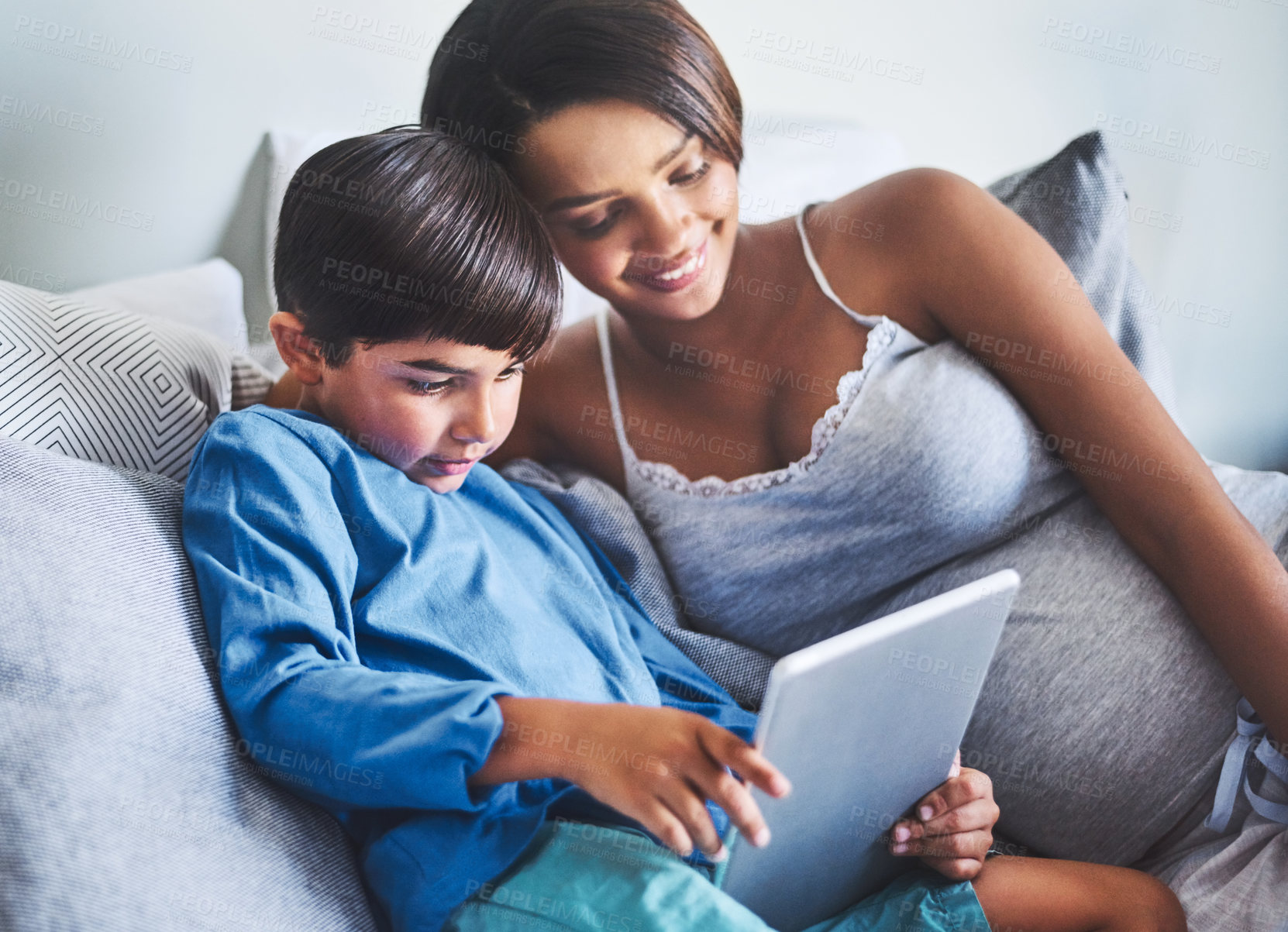 Buy stock photo Cropped shot of an adorable little boy and his pregnant mother using a laptop while relaxing on her bed