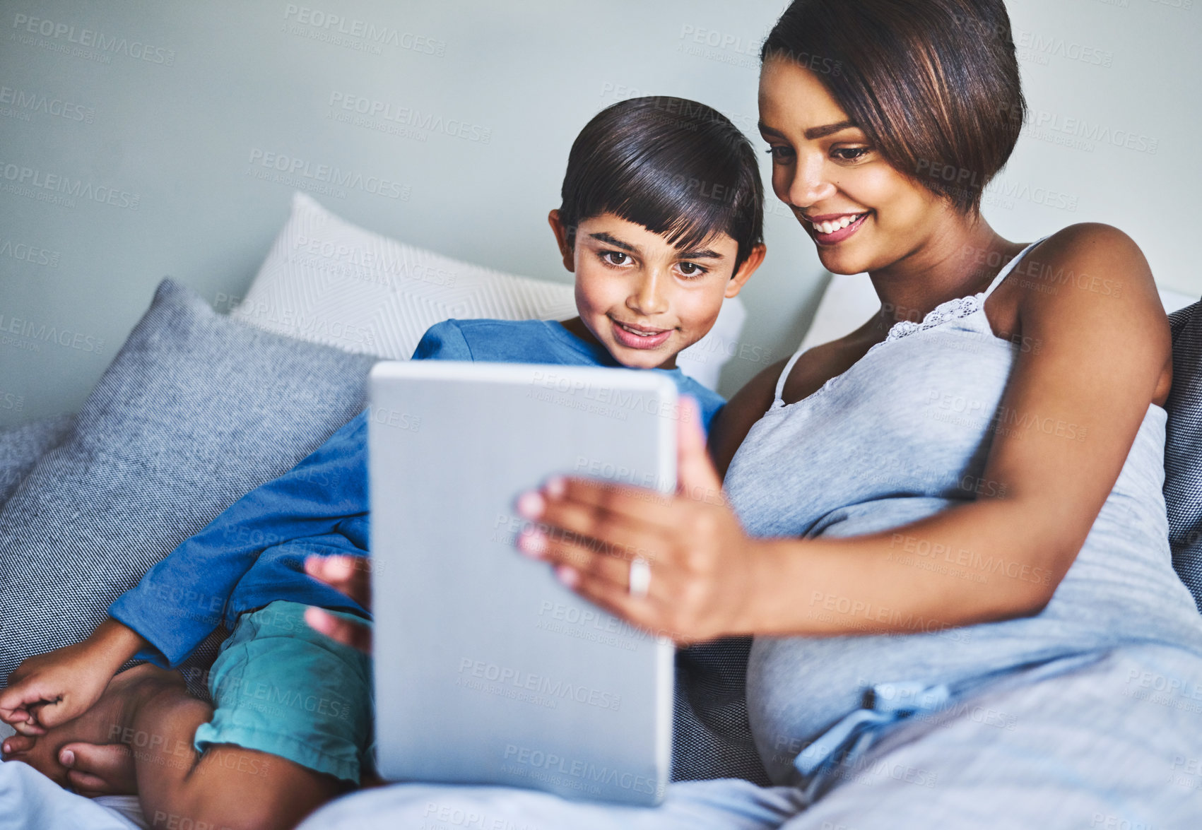 Buy stock photo Cropped shot of an adorable little boy and his pregnant mother using a laptop while relaxing on her bed