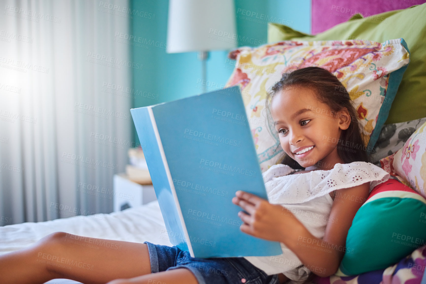 Buy stock photo Shot of an adorable little girl reading a book at home