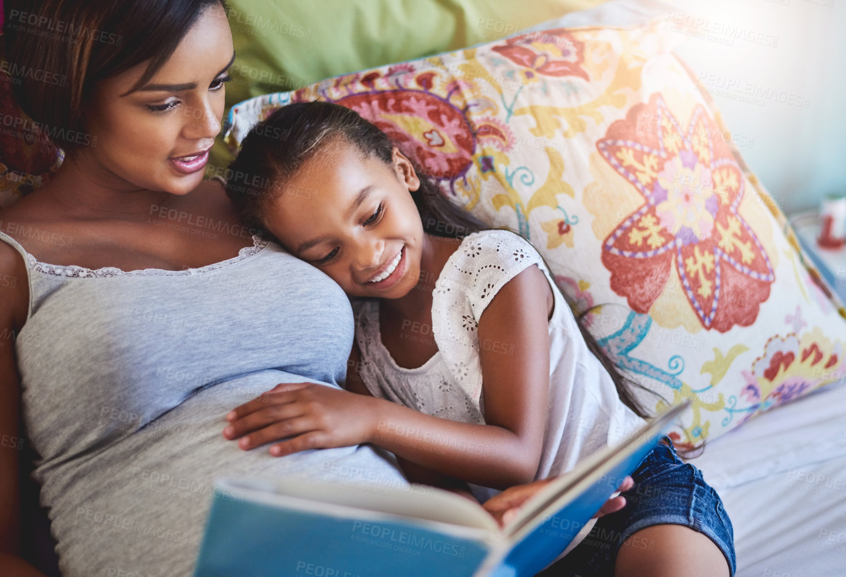 Buy stock photo Shot of a mother reading a story to her little daughter at home