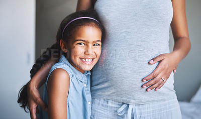 Buy stock photo Portrait of a cheerful little girl standing with her arms around her pregnant other at home during the day