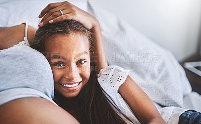 Buy stock photo Portrait of a cheerful little girl lying and relaxing next to her pregnant mother at home during the day