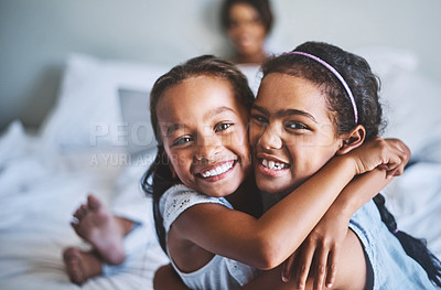 Buy stock photo Portrait of two cheerful little girls with arms around each other while their pregnant mother relaxes in the background with a laptop