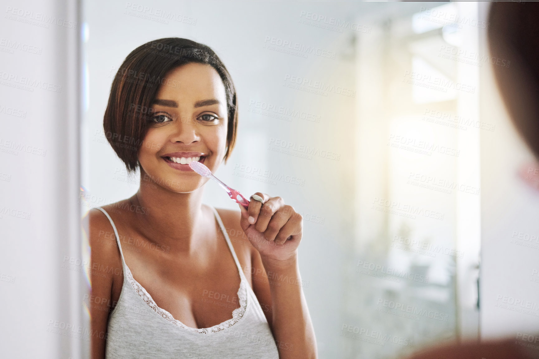Buy stock photo Portrait of an attractive young woman brushing her teeth in the bathroom