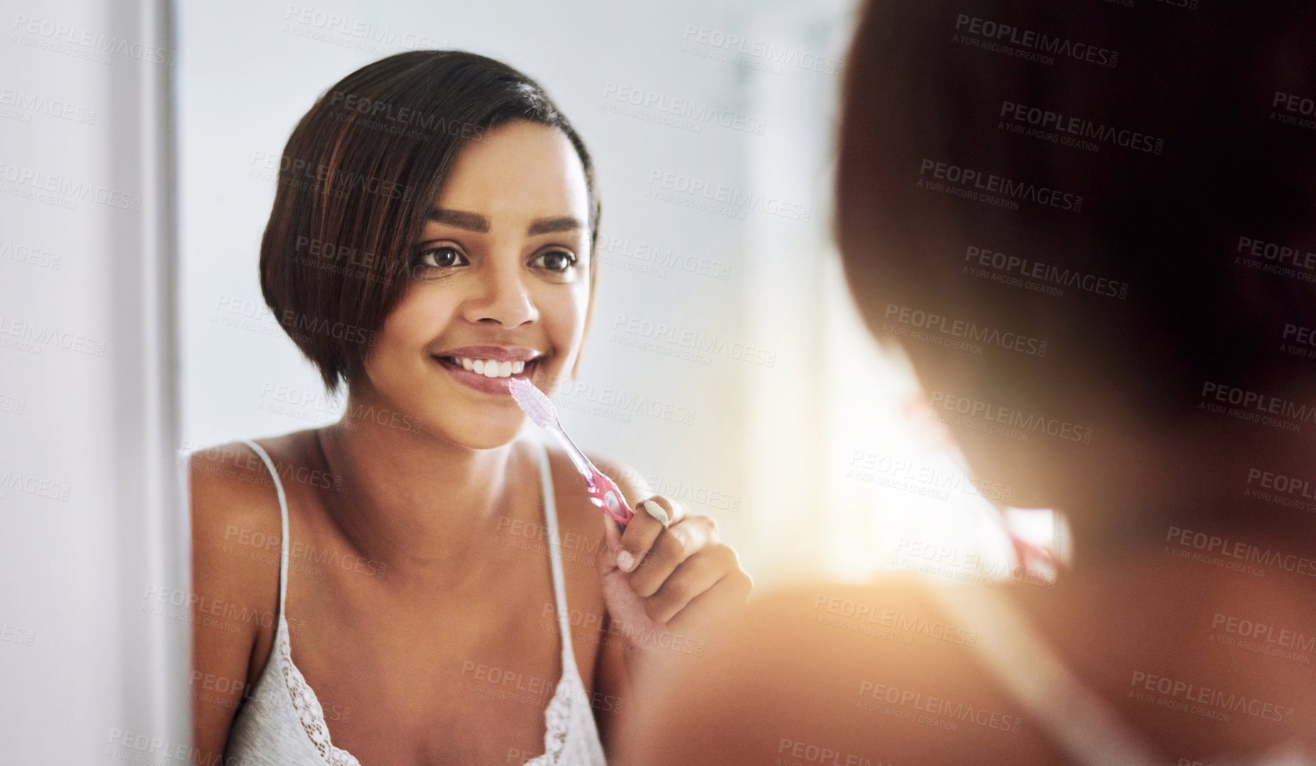 Buy stock photo Shot of an attractive young woman brushing her teeth in the bathroom