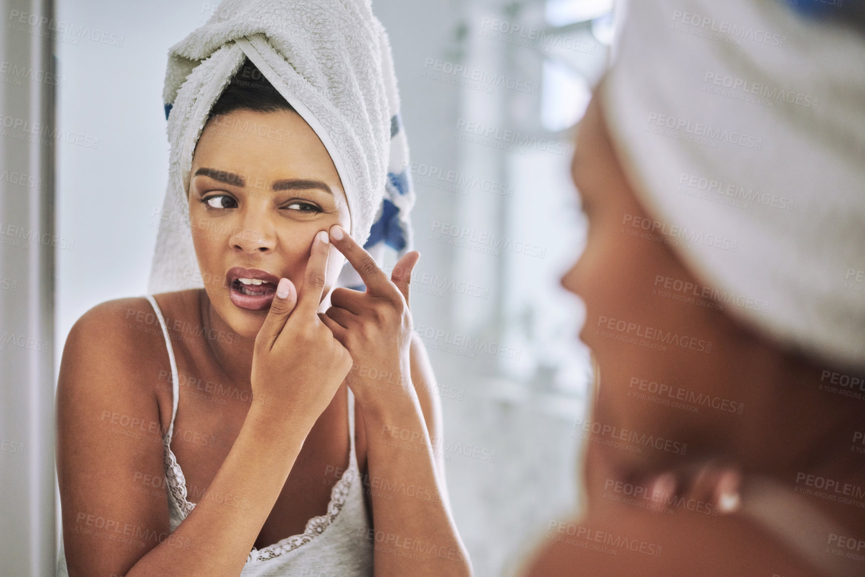 Buy stock photo Shot of an attractive young woman squeezing a pimple on her face in the bathroom