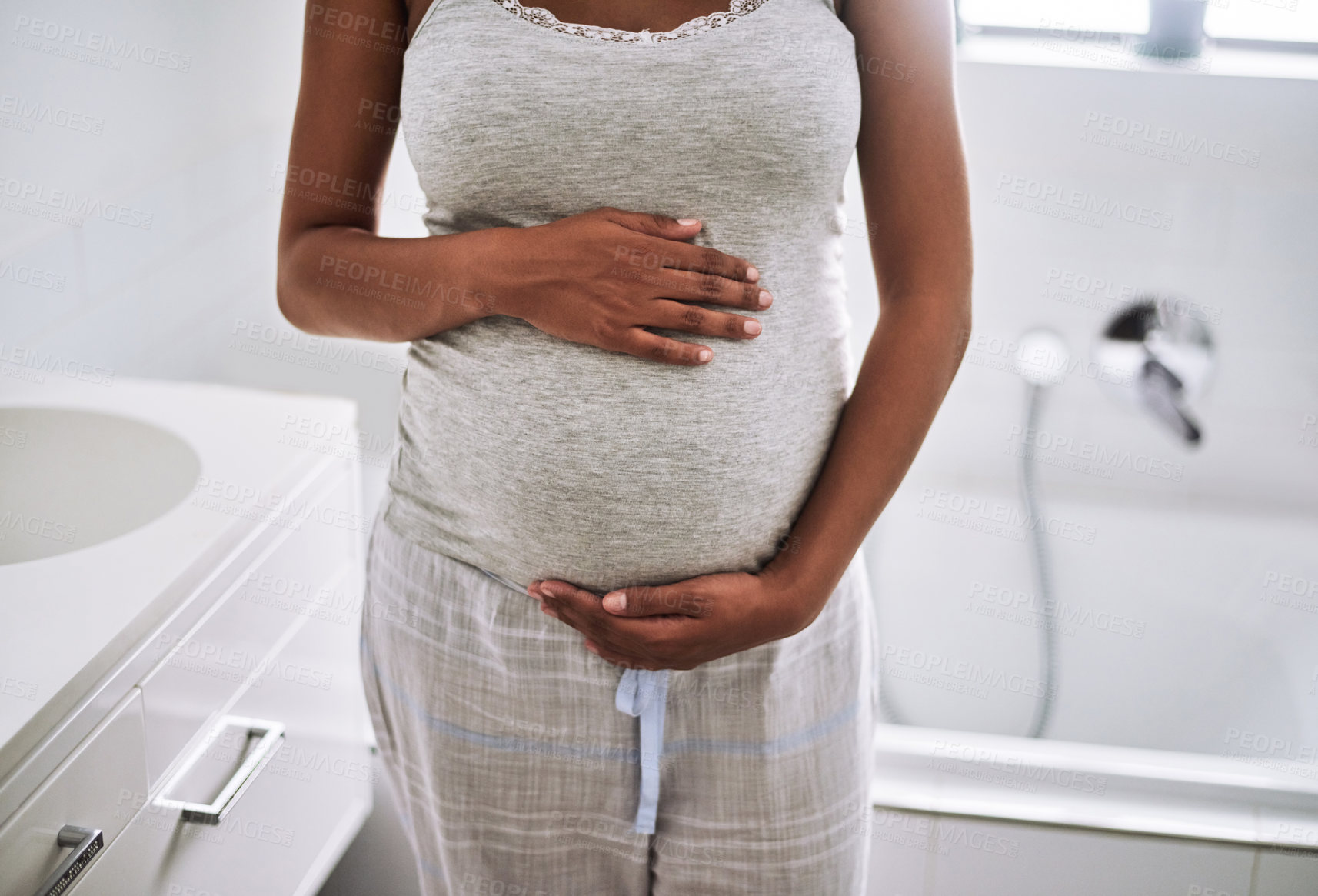 Buy stock photo Closeup shot of a pregnant woman standing in the bathroom at home