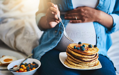 Buy stock photo Cropped shot of a pregnant woman eating delicious pancakes at home
