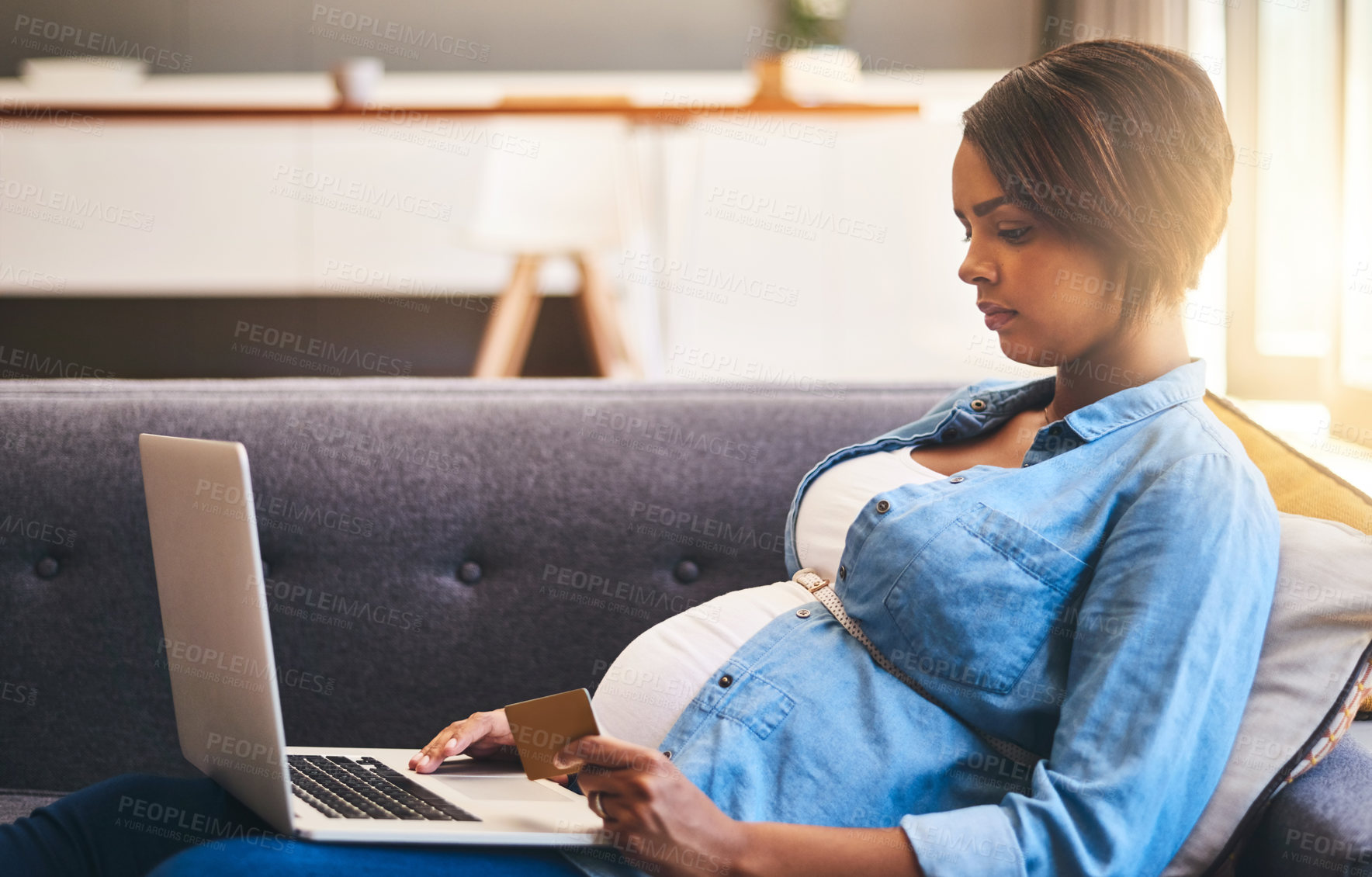 Buy stock photo Cropped shot of a pregnant woman using a laptop and credit card on the sofa at home