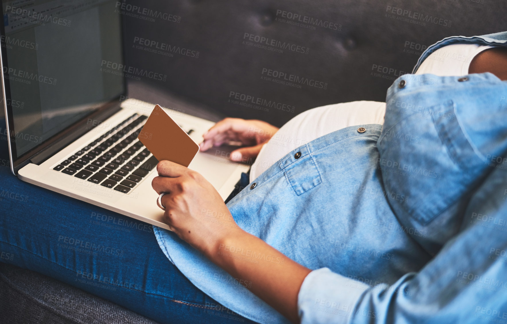 Buy stock photo Cropped shot of a pregnant woman using a laptop and credit card on the sofa at home