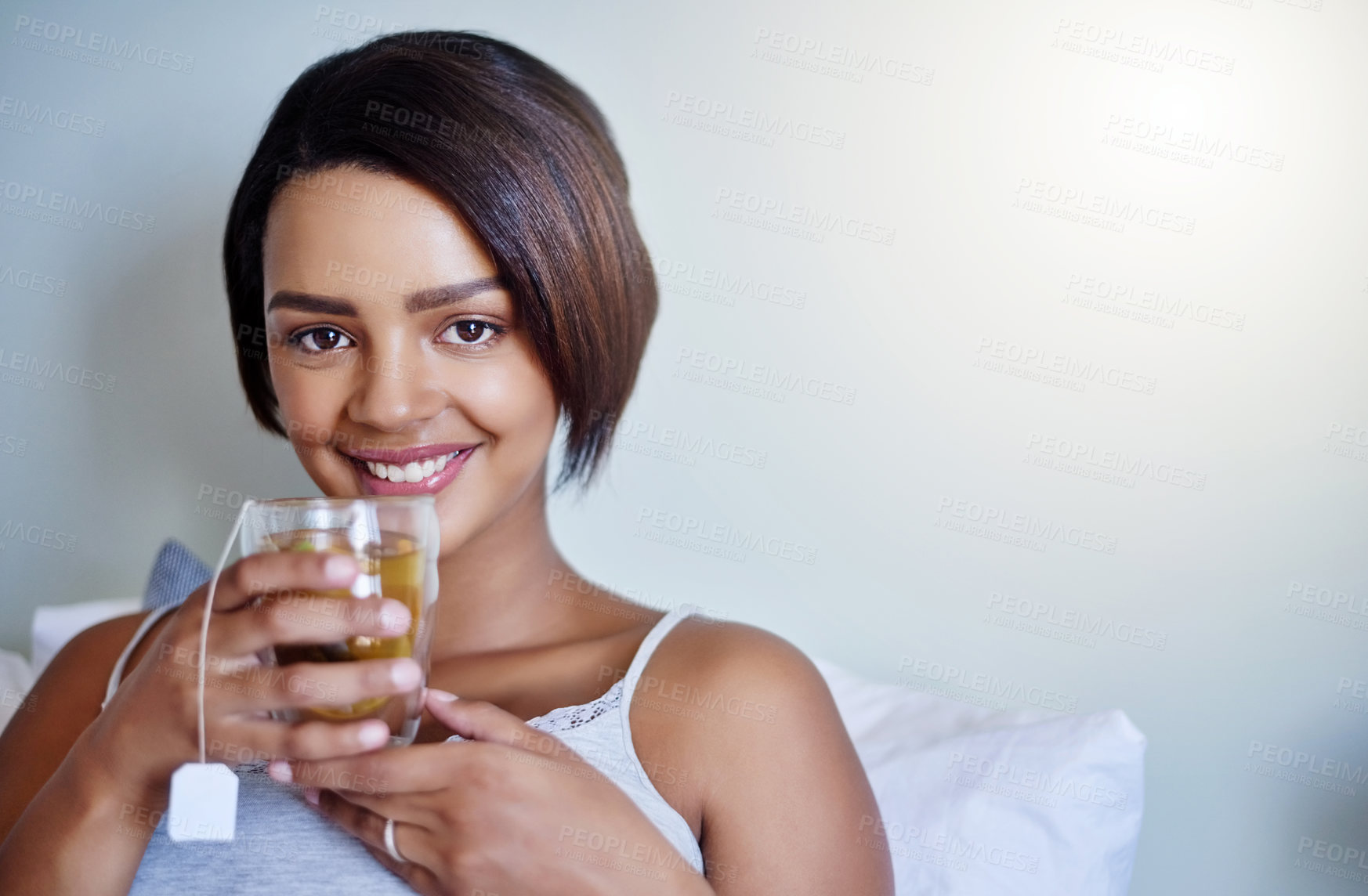 Buy stock photo Shot of an attractive young woman relaxing at home with a glass of tea