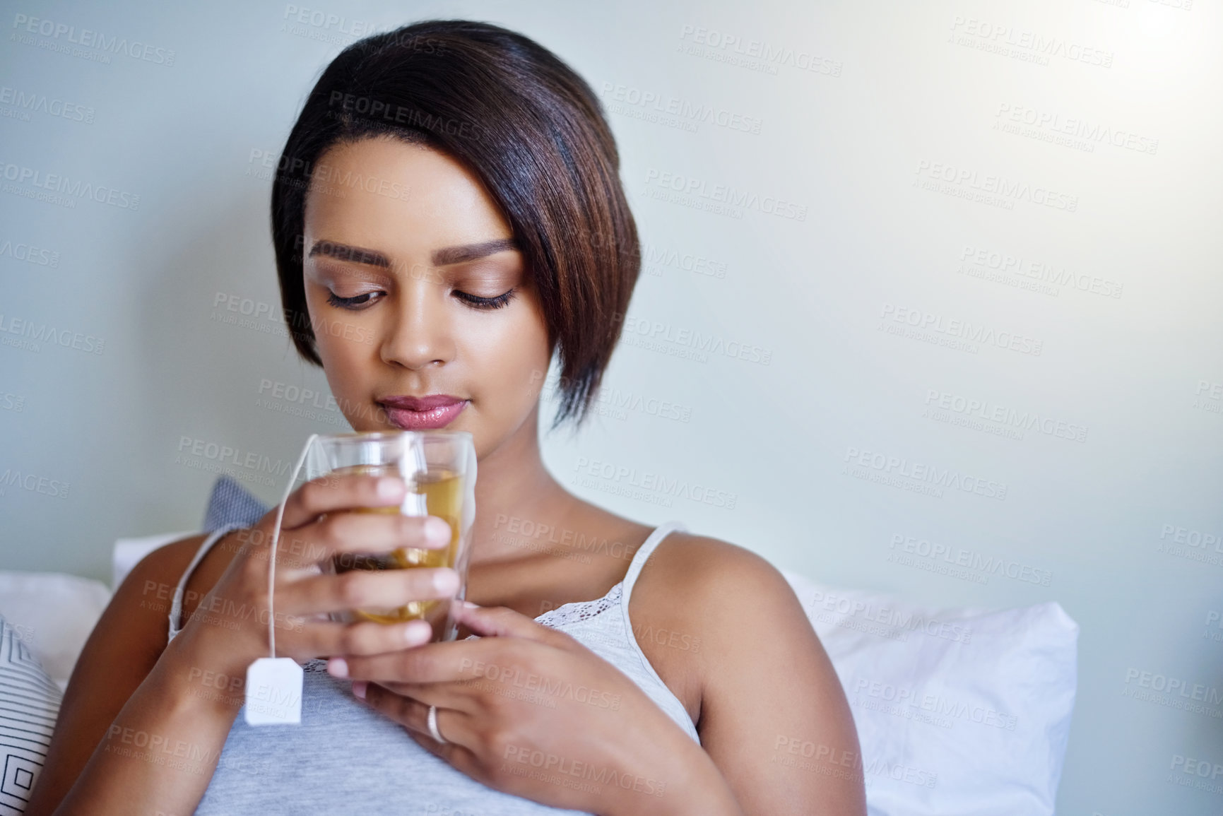Buy stock photo Shot of an attractive young woman relaxing at home with a glass of tea