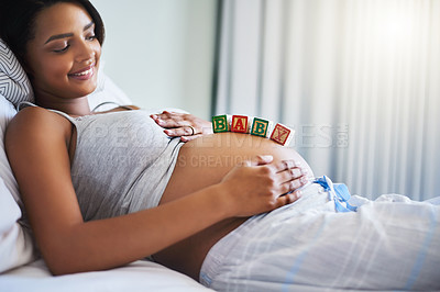 Buy stock photo Shot of a young pregnant woman with wooden blocks on her belly that spell the word baby