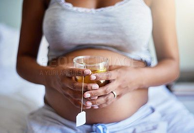Buy stock photo Cropped shot of a pregnant woman relaxing at home with a glass of tea