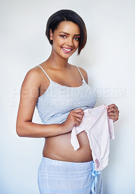 Buy stock photo Baby clothes, pregnancy and portrait of woman in studio with family planning for future. Happy, prenatal care and pregnant female person with romper by belly bump for bonding by white background.