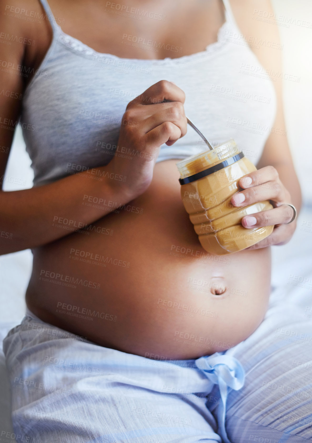Buy stock photo Cropped shot of a pregnant woman eating from a jar of peanut butter at home
