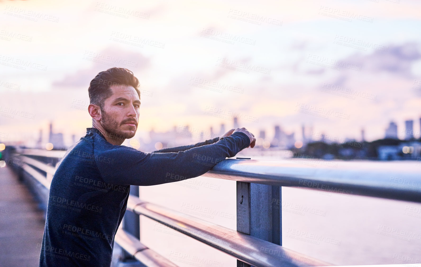 Buy stock photo Shot of a sporty young man taking a break while exercising outdoors