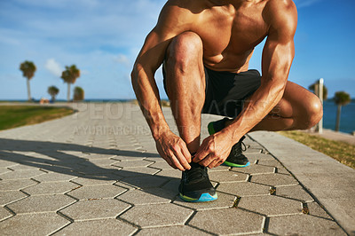 Buy stock photo Closeup shot of an unrecognizable man tying his shoelaces while exercising outdoors
