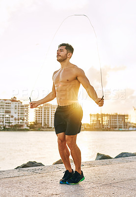 Buy stock photo Shot of a handsome young man using a skipping rope outdoors