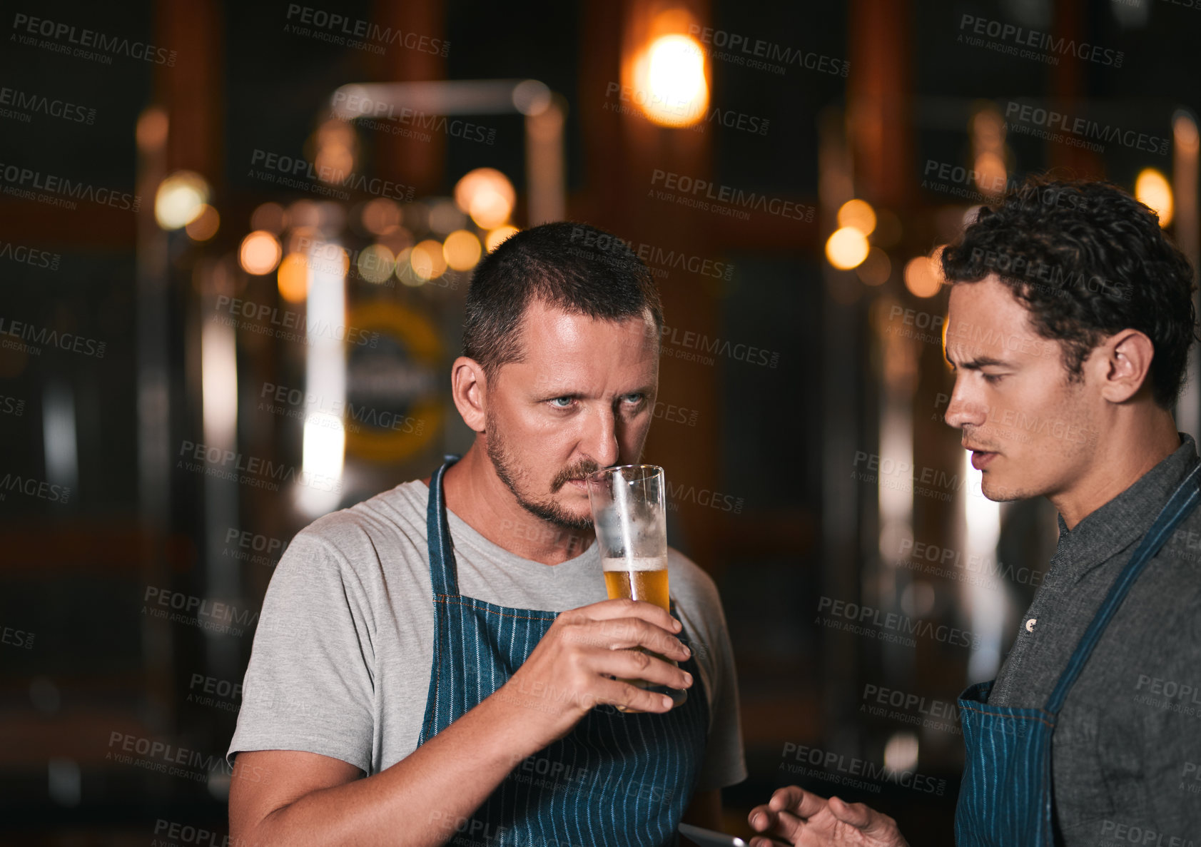 Buy stock photo Shot of two working businessmen tasting beer inside of a beer brewery during the day