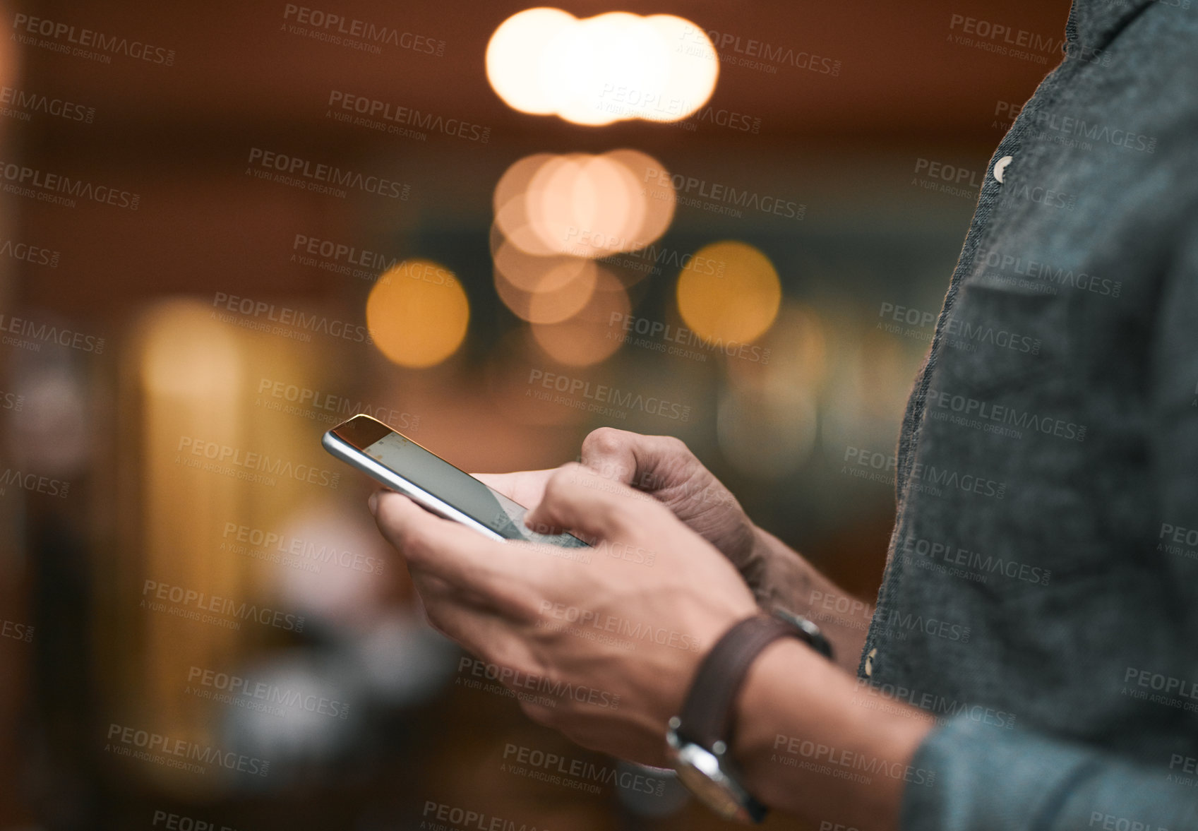 Buy stock photo Shot of an unrecognizable man browsing on a cellphone while standing inside of a beer brewery during the day