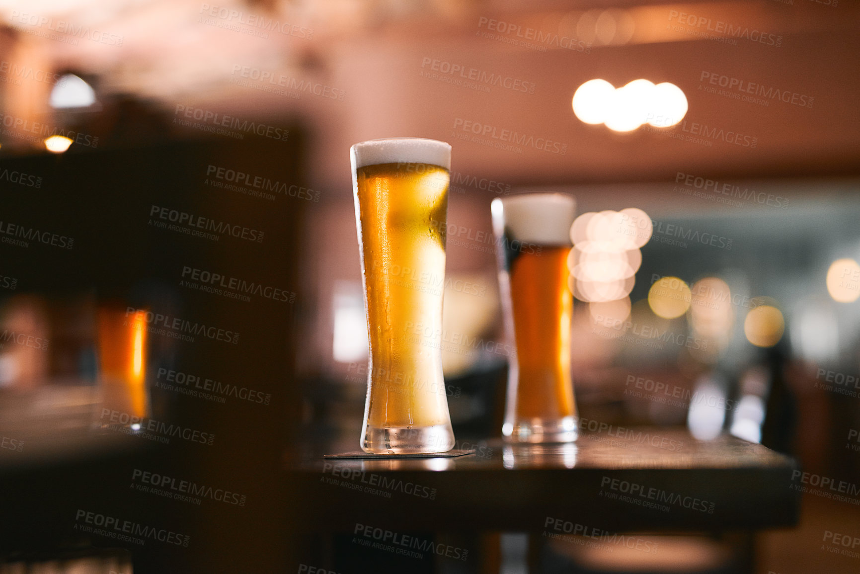 Buy stock photo Shot of two glasses of beer standing on its own at a table  inside of a beer brewery during the day
