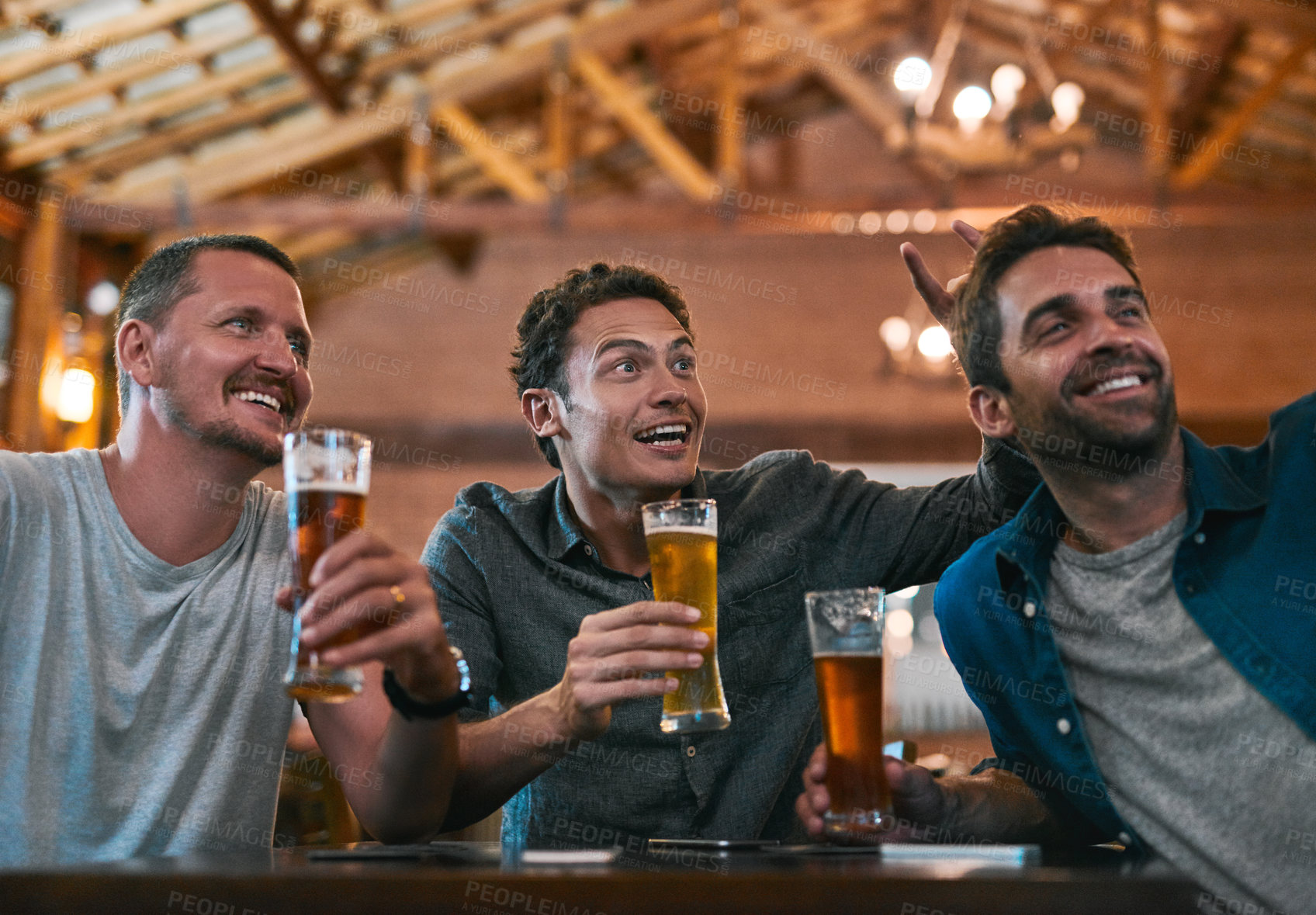 Buy stock photo Shot of three young cheerful men drinking beer at a table while taking a self portrait together inside of a beer brewery