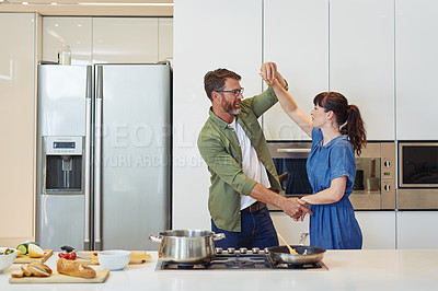 Buy stock photo Shot of a mature couple dancing while cooking together at home