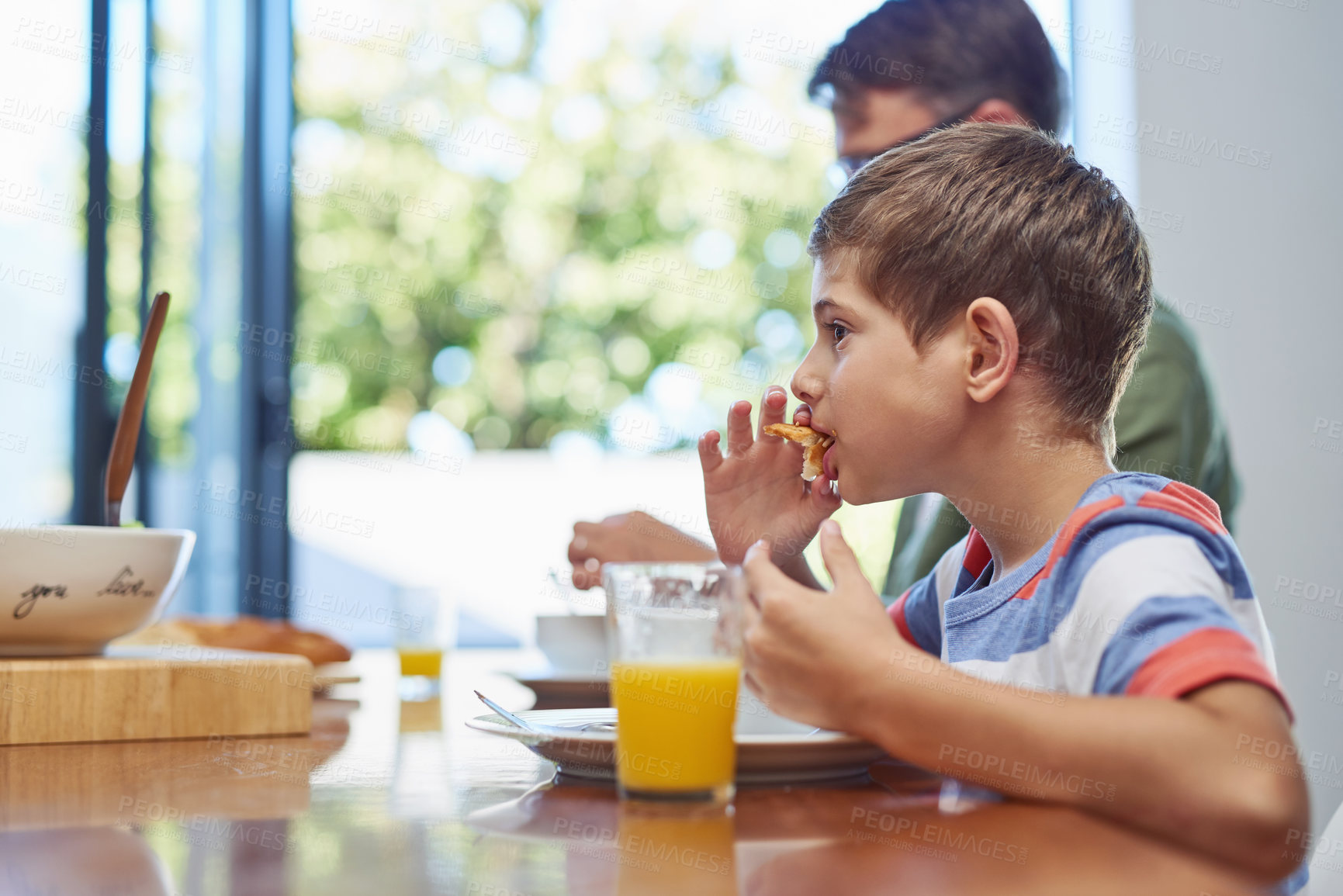 Buy stock photo Shot of a little boy enjoying a meal with his father at home