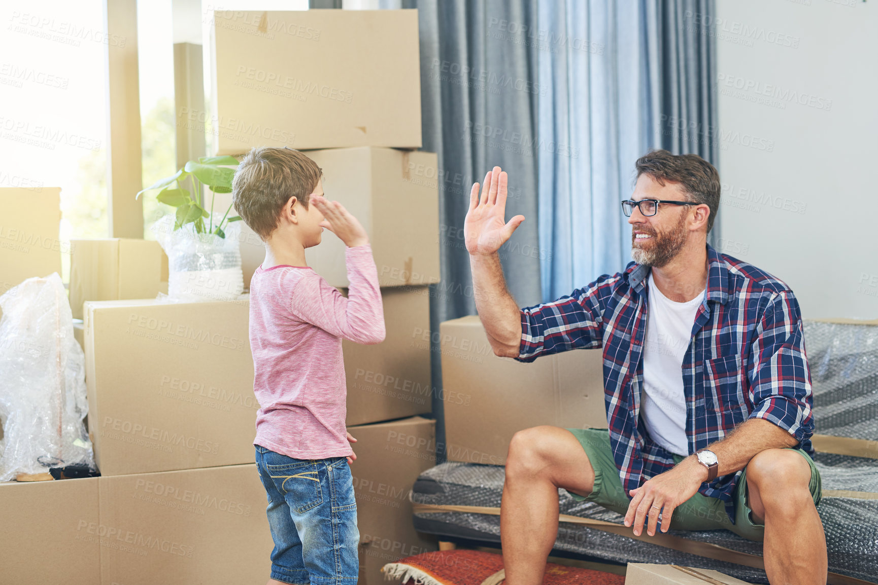 Buy stock photo Shot of a happy father and son giving each other a high five on moving day
