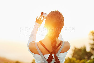 Buy stock photo Rearview shot of an unrecognizable woman taking a photo using her cellphone in nature