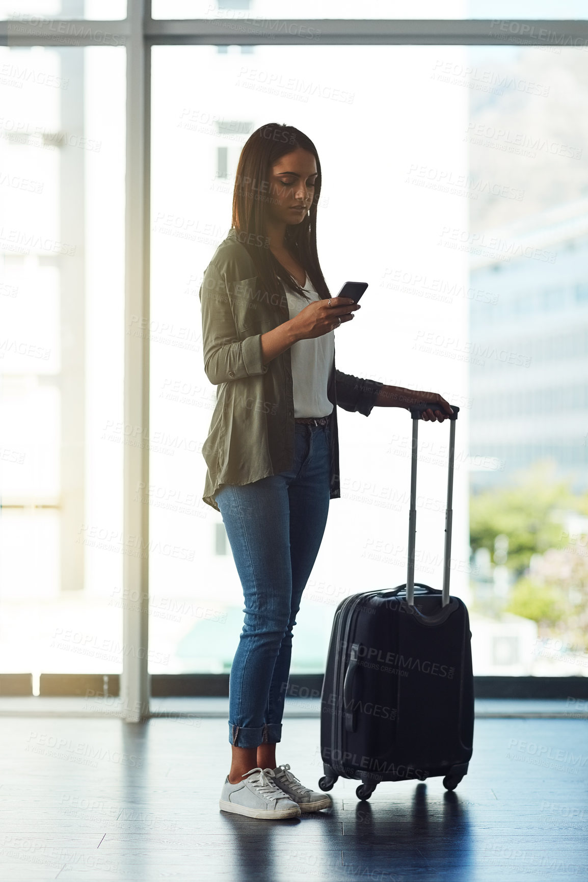 Buy stock photo Shot of an attractive young woman using a cellphone in an airport