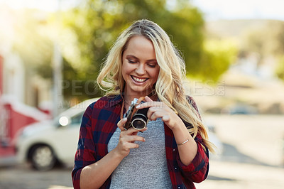 Buy stock photo Cropped shot of a young beautiful woman looking at photographs on a camera in the city