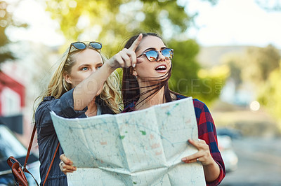 Buy stock photo Cropped shot of two beautiful female friends looking at a map for directions in the city