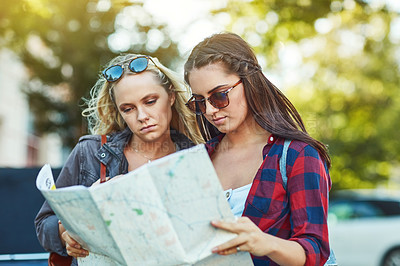 Buy stock photo Cropped shot of two beautiful female friends looking at a map for directions in the city