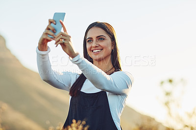 Buy stock photo Cropped shot of a beautiful young woman taking a selfie in nature