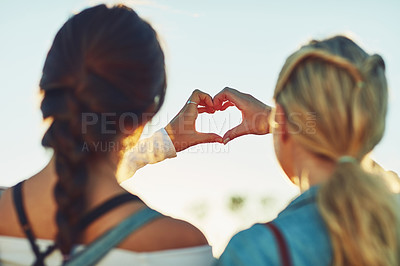 Buy stock photo Rearview shot of two unrecognizable female friends making a heart shape with their hands in nature