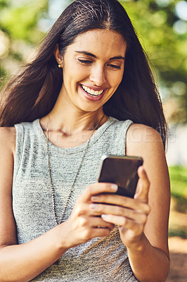 Buy stock photo Shot of an attractive young woman using a cellphone outdoors