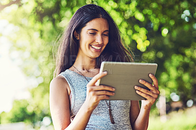 Buy stock photo Shot of an attractive young woman using a digital tablet outdoors