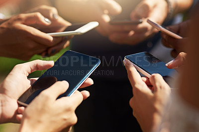 Buy stock photo Shot of a group of people using their cellphones in synchronicity outdoors