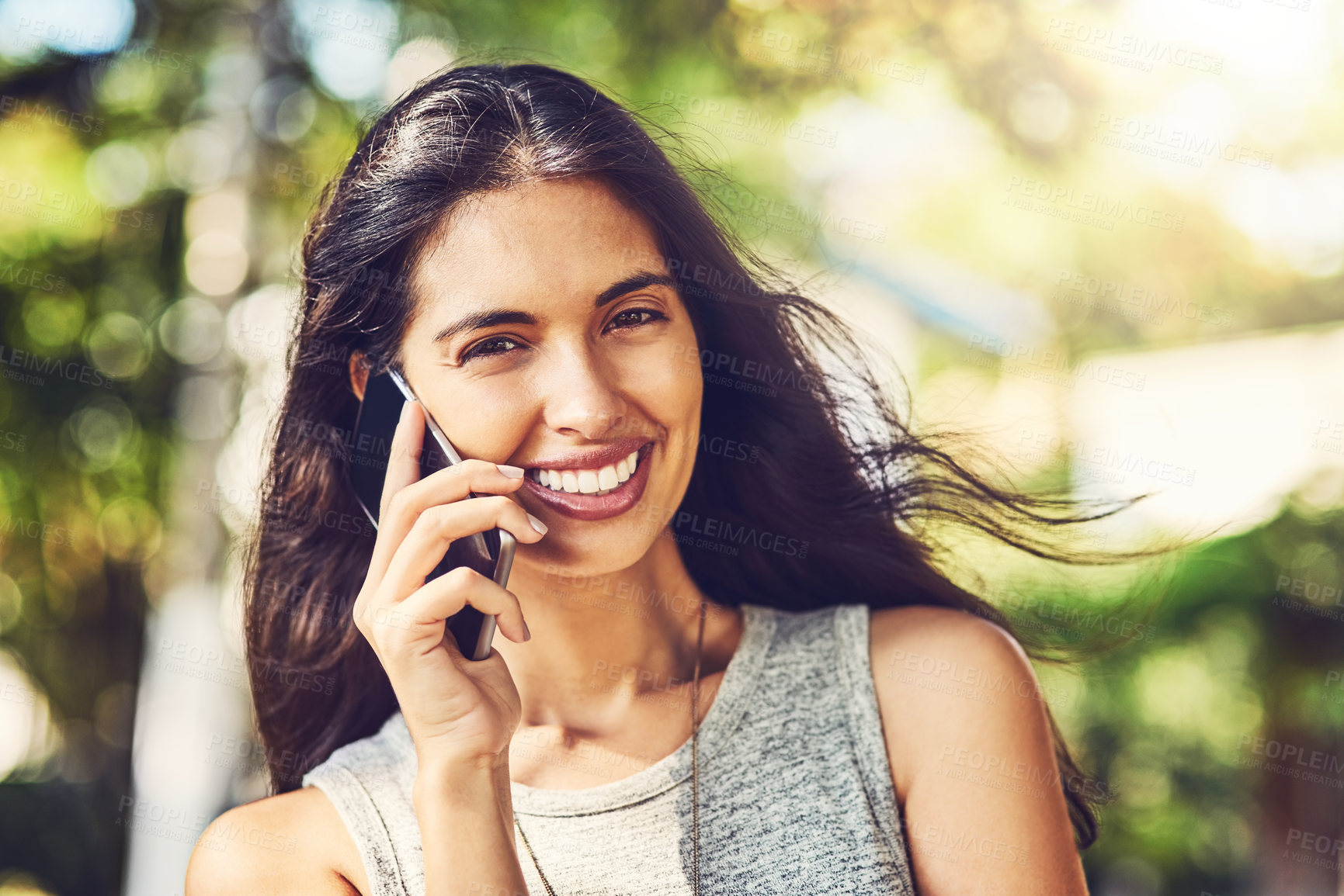 Buy stock photo Portrait of an attractive young woman talking on a cellphone outdoors