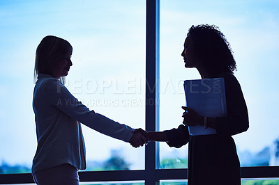 Buy stock photo Silhouette of two unrecognizable businesswomen shaking hands in the office