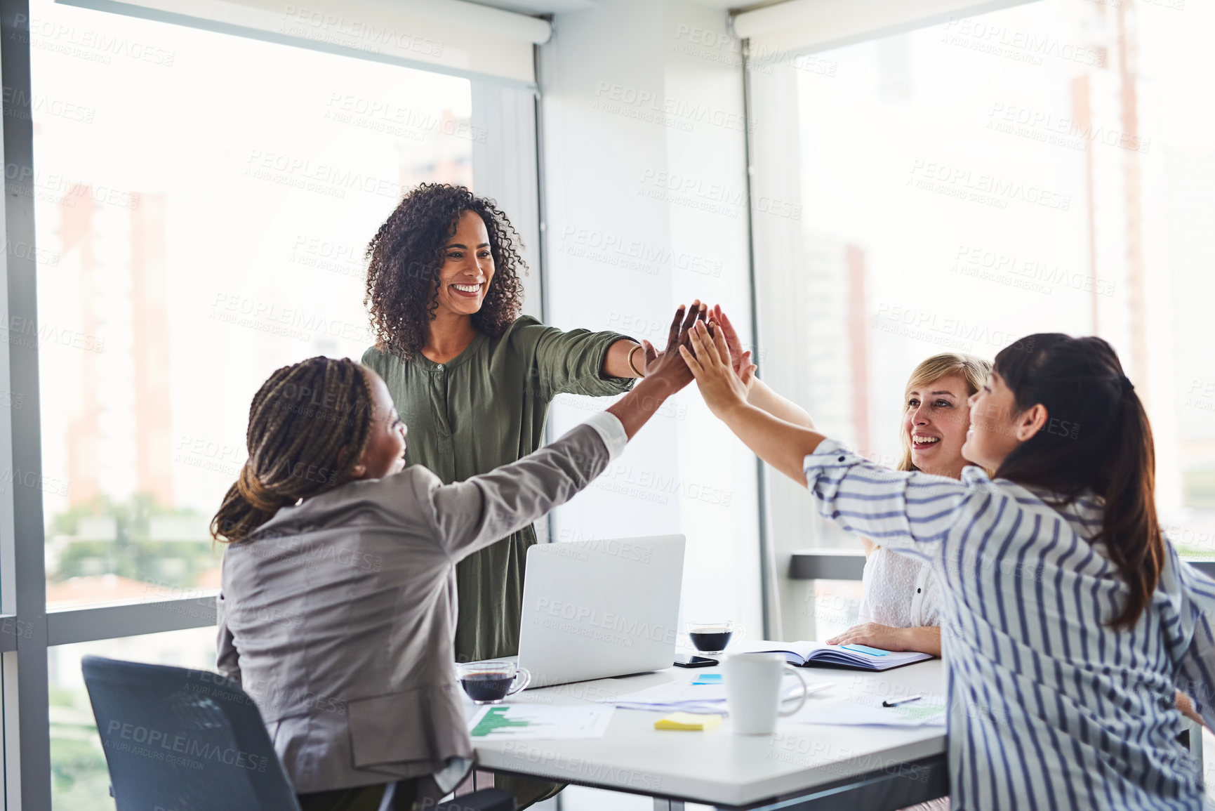 Buy stock photo Cropped shot of a group of businesswomen giving each other a high five in the office