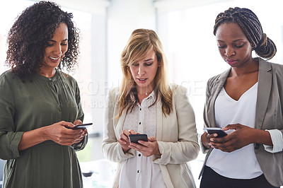Buy stock photo Cropped shot of a group of businesswomen using cellphones in the office