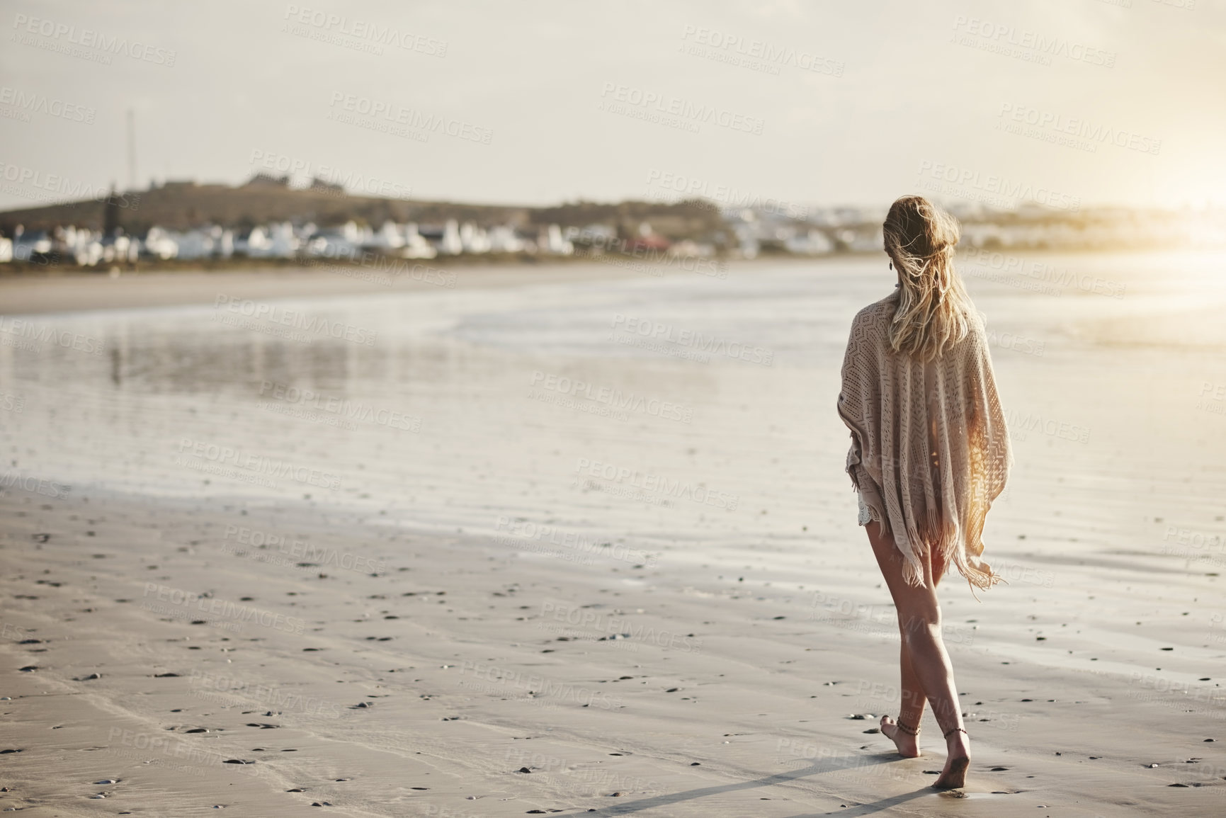 Buy stock photo Rearview shot of a young woman walking along the seashore