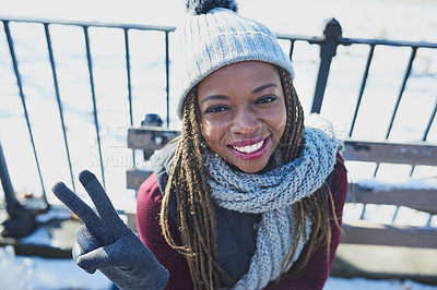 Buy stock photo Shot of a beautiful young woman making a peace gesture on a snowy day outdoors