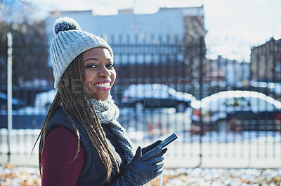 Buy stock photo Shot of a beautiful young woman using a mobile phone on a snowy day outdoors