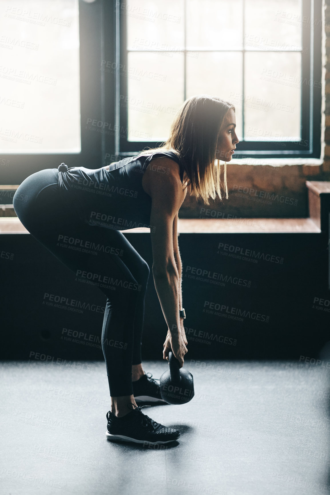 Buy stock photo Shot of a young woman working out with a kettle bell in a gym