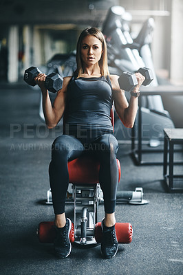 Buy stock photo Shot of a young woman working out with weights in a gym