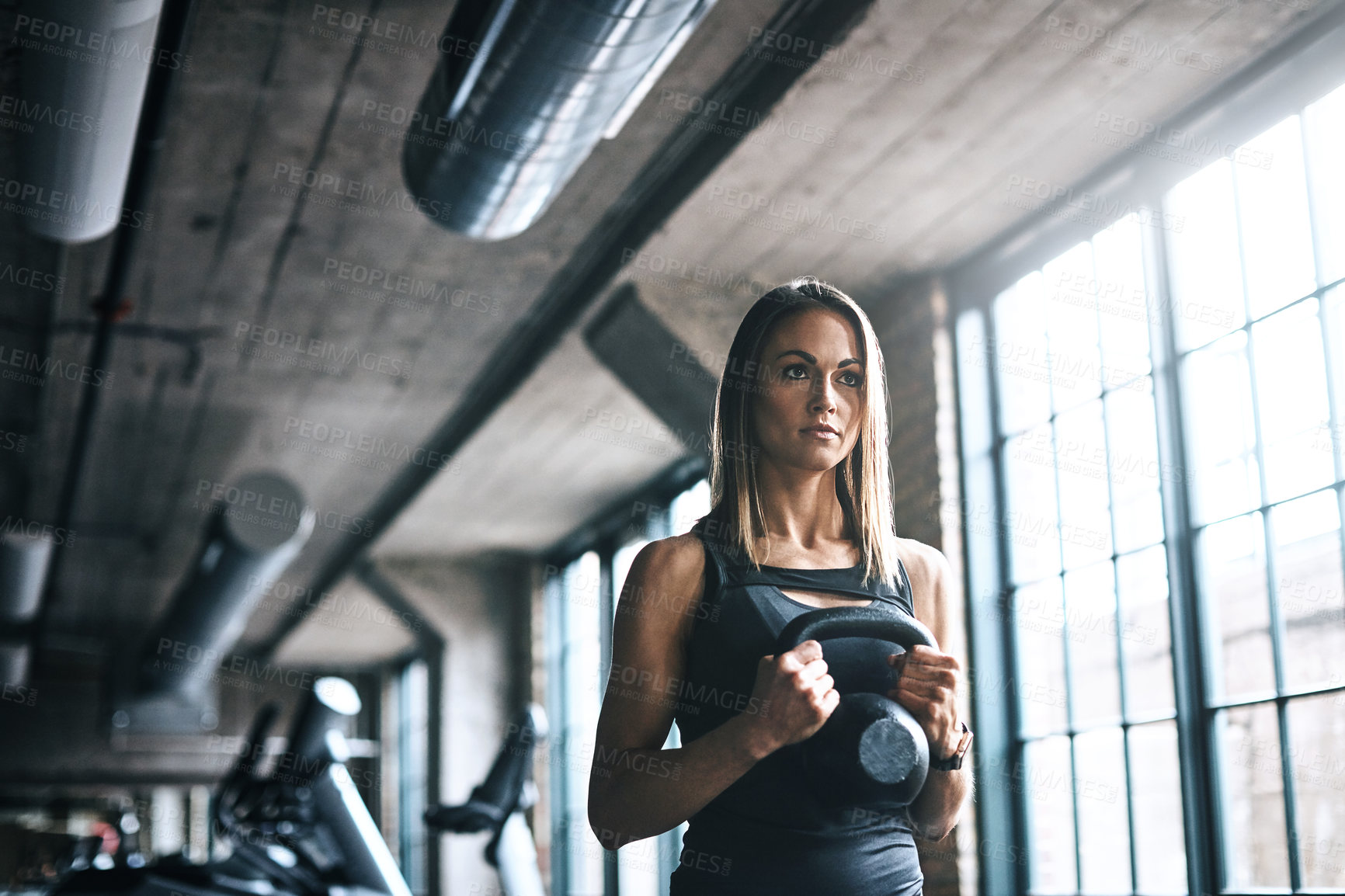 Buy stock photo Shot of a young woman working out with a kettle bell in a gym